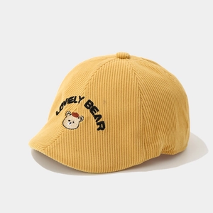Detailed view of yellow corduroy baby cap featuring a cute embroidered bear and text