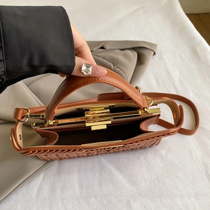 Brown woven texture handbag with gold metal clasp shown with top handle and strap