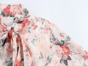 Detail of pink chiffon floral dress showing sheer fabric texture and neckline ribbon tie