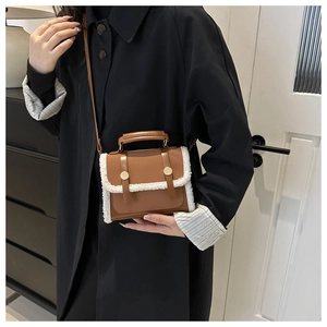 Close-up of brown crossbody bag with white faux shearling trim and gold buckle detail