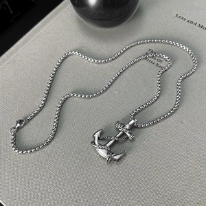 Detailed view of a silver anchor cross pendant necklace displayed on an open vintage book