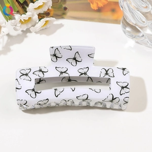 Macro view of white butterfly print hair claw clip on acrylic base with floral background