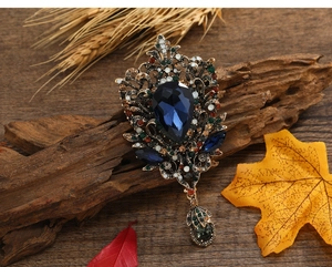 Detail of vintage bronze brooch with large blue teardrop gem and colorful rhinestones