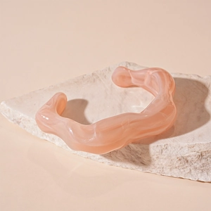 Macro shot of pink acrylic irregular wavy open bangle on natural stone display