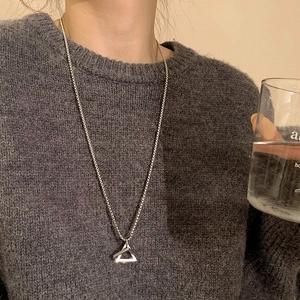 Polished silver stainless steel double triangle pendant necklace on a grey sweater
