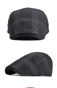 Detail of dark grey plaid corduroy flat cap showing fine texture and structured design
