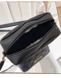 Close-up of black quilted small square bag with dual gold zippers and interior space