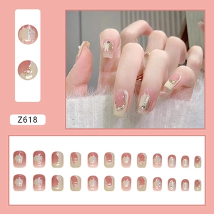 Detail of pink blush press-on nails featuring elegant pearls and gold glitter accents