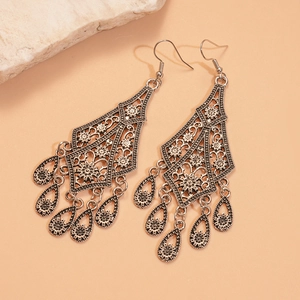 Detailed view of vintage silver hollow flower drop fringe earrings on white rock