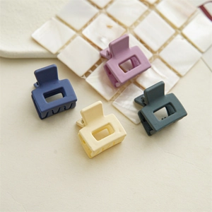 Close-up of four matte square hair claws in blue, purple, grey, and yellow Morandi tones