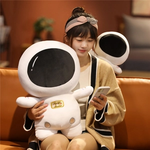 A person holding a soft plush astronaut doll with gold details in a warm home setting