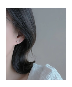 Close-up of a minimalist small pearl screw back stud earring worn on the earlobe