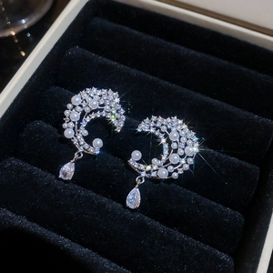 Detail of silver moon stud earrings with pearls and crystals on black velvet display