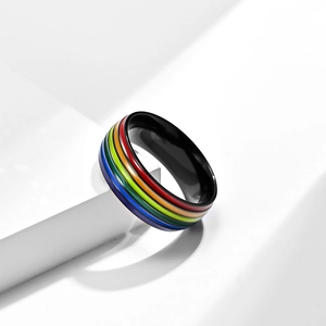 Minimalist black stainless steel ring with vibrant rainbow stripes on a white pedestal