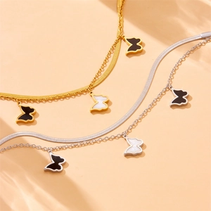 Macro detail of layered gold and silver butterfly necklaces with sleek snake chain texture