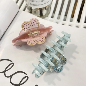 Detail view of pink and blue acetate hair claws with sparkling rhinestones on a white page