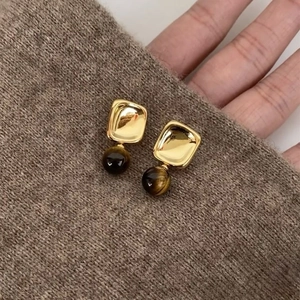 Detail of vintage gold plated square earrings with brown stone bead on knit sweater