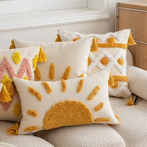 Detail of boho tufted pillow with mustard yellow sun pattern and cotton tassels