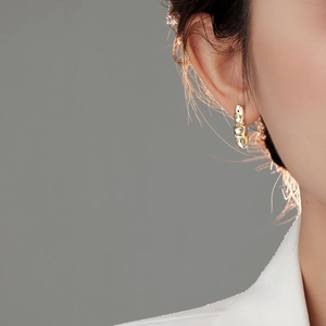 Close-up detail of golden irregular lava earring with S925 hallmark on polished metal