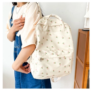 Detail of cream floral backpack featuring pink flower patterns and sturdy double handles