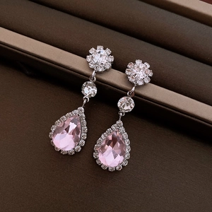 Detail of teardrop pink crystal drop earrings with silver finish on bronze textured surface