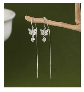 Close-up of S925 silver bow tassel earrings with sparkling crystals on dark background