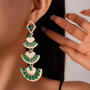 Close-up of luxury emerald fan drop earrings with silver pins and white pavé crystals