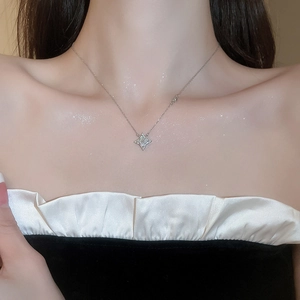 Close-up of a silver four-point star necklace with shiny crystals on a female model