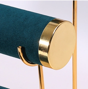 Detail of teal velvet rod with golden metal end cap on a multi-tier jewelry stand