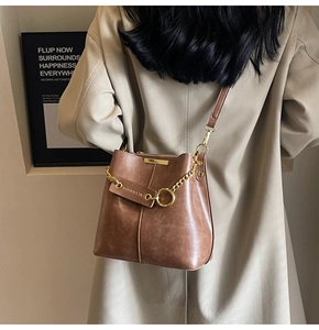 Macro shot of brown retro leather bucket bag with gold chain and metal hardware texture