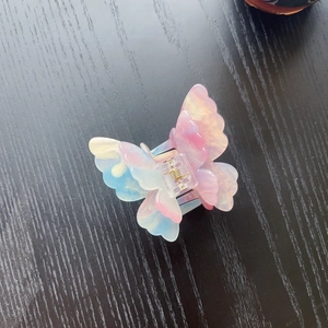 Detailed top view of a gradient butterfly hair claw with marble texture on wood