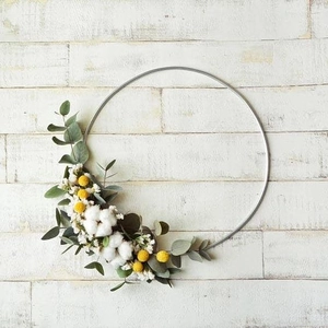 Close-up of metal floral hoop with eucalyptus leaves and cotton flowers on wood