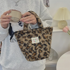 Detail of leopard print faux fur handbag with zipper closure and brand label