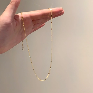 Détail d'un collier minimaliste doré avec chaîne fine et breloque en forme de goutte
