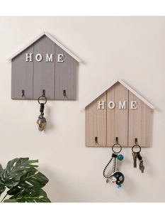 Detail of house-shaped wooden key rack with HOME text and three vintage bronze metal hooks
