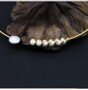 Artistic detail of a handmade gold wire choker with natural white freshwater pearls