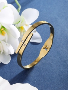 Detail of gold-plated bangle featuring two sparkling zircons and a secure hinge closure