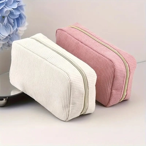 Detailed view of white and pink corduroy makeup bags with gold zippers and soft texture