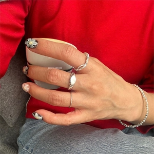 Close-up of minimalist 925 silver rings and bead bracelet worn with casual attire
