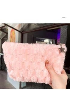 Close-up of pink plush checkerboard makeup bag with silver star charm and metal zipper