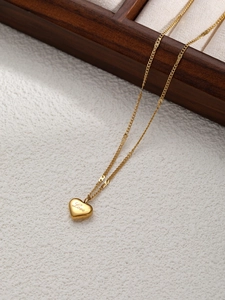 Dettaglio del ciondolo a cuore dorato con incisione Love su una catena sottile