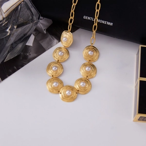 Detail of vintage gold-tone clover necklace with spiral textures and white pearls
