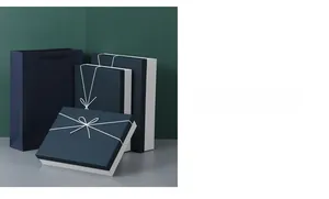 Three deep blue gift boxes with white bows and a matching gift bag in a minimalist setting