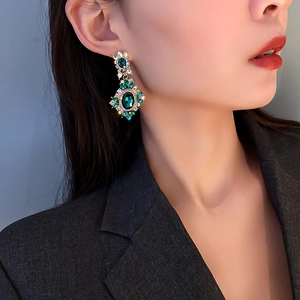 Macro view of vintage emerald flower earrings with pavé crystals on elegant female model
