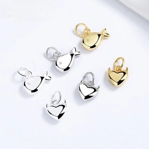 Detail view of fish and devil heart pendants in gold and silver finishes with top rings
