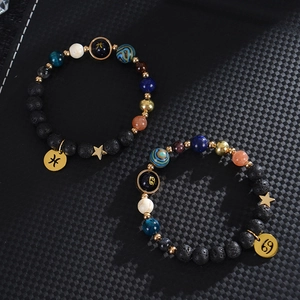 Solar system planet bracelet with natural stones and gold zodiac charms on carbon background