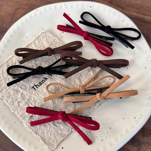 Suede red and neutral bow hair clips collection displayed on a white ceramic plate