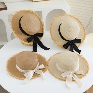Flat top straw sun hats with black and beige ribbons and fringe edges in a set of four
