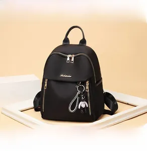Close-up of black Oxford backpack with gold zippers and a bear keychain accessory