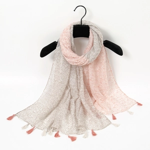 Detail of pink and gray ink floral print scarf with soft tassels on a white background